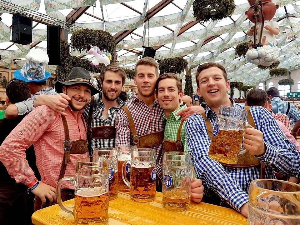 Friends celebrating with beer steins inside an Oktoberfest tent in Munich